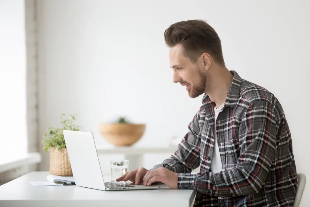 smiling-man-freelancer-working-laptop-communicating-online-using-software